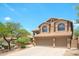 Two-story home with a three-car garage, neutral stucco, and a tile roof surrounded by mature trees at 10490 E Morning Star Dr, Scottsdale, AZ 85255