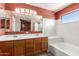 Bright bathroom boasts dual sinks, white countertops, bathtub, and a large mirror at 1121 W Windjammer Dr, Gilbert, AZ 85233