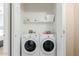 A convenient laundry room featuring a front-load washer and dryer, and storage shelves at 11375 E Sahuaro Dr # 2015, Scottsdale, AZ 85259