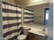 Bathroom features a single sink vanity, commode, and shower with stylish striped shower curtain at 11921 W Madison St, Avondale, AZ 85323