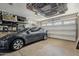 Organized garage space featuring a gray electric vehicle, overhead storage racks, and epoxy flooring at 12738 W Brookhart Way, Peoria, AZ 85383