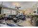 Spacious living room with large windows, ceiling fan, leather furniture, and tile flooring at 12738 W Brookhart Way, Peoria, AZ 85383