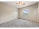 A standard bedroom features neutral paint, carpet, a ceiling fan, and a window at 13633 W Alvarado Dr, Goodyear, AZ 85395