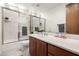 Bright bathroom featuring wood vanity, modern sink, tiled floors, and a glass-enclosed shower with gray towels at 15953 N 111Th Way, Scottsdale, AZ 85255