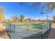 Fenced tennis courts with green surface surrounded by recreation area, lights, and desert landscaping at 16404 S 18Th Dr, Phoenix, AZ 85045