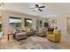 Cozy living room with a ceiling fan, neutral-toned furniture, and bright natural light from large windows at 16716 W Rincon Peak Dr, Surprise, AZ 85387