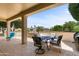 Covered outdoor patio area with stylish seating and a view of the well maintained backyard at 16716 W Rincon Peak Dr, Surprise, AZ 85387