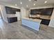 Stylish kitchen showcasing dark cabinets, a large island with granite countertops, tile floors, and recessed lighting at 18230 W Poston Dr, Surprise, AZ 85387
