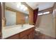 Well-lit bathroom featuring a large mirror, single sink vanity, and bathtub with a shower at 2229 S 82Nd Ln, Phoenix, AZ 85043