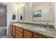 Bathroom featuring double sinks, granite countertop, wood cabinets and dual mirrors at 3089 E Indigo Bay Dr, Gilbert, AZ 85234
