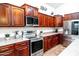 Beautiful cherry wood kitchen with stainless steel appliances, light countertops, and an adjacent stainless steel refrigerator at 3511 W Allens Peak Dr, San Tan Valley, AZ 85144