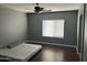 A bedroom with laminated wood floor, ceiling fan, and a window for natural light at 38242 N Armadillo Dr, San Tan Valley, AZ 85140