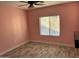 An empty bedroom with light pink walls, ceiling fan, window, and light-colored tile flooring at 38242 N Armadillo Dr, San Tan Valley, AZ 85140
