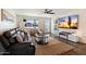 Comfortable living room features a plush black sofa, large TV, and lots of natural light from the window and glass paneled door at 4136 E Eugie Ave, Phoenix, AZ 85032