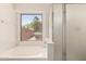 Bright bathroom features a garden tub, frosted shower door, and a view of the backyard at 42458 W Desert Fairways Dr, Maricopa, AZ 85138
