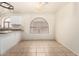 Cozy dining area adjacent to kitchen with tile floors and a charming arched window at 42458 W Desert Fairways Dr, Maricopa, AZ 85138