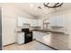 Well-lit kitchen featuring white cabinetry, black appliances, and a U-shaped countertop layout at 42458 W Desert Fairways Dr, Maricopa, AZ 85138