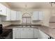 Bright kitchen featuring white cabinets, neutral countertops, and a window above the sink at 42458 W Desert Fairways Dr, Maricopa, AZ 85138