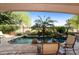 A picturesque pool area with lush greenery, palm trees, rock features and clear blue water, perfect for relaxation at 4548 E Nightingale Ln, Gilbert, AZ 85298