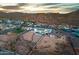 Expansive aerial view of a desert home featuring a pool, desert landscaping, and mountain views at sunset at 460 W Chase St, San Tan Valley, AZ 85143