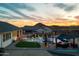 Stunning backyard featuring a pool, putting green, outdoor kitchen, and scenic mountain views at sunset at 460 W Chase St, San Tan Valley, AZ 85143