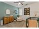 Bedroom with green accent wall, wooden crib, dresser with changing table, comfortable chair, and decorative elements at 460 W Chase St, San Tan Valley, AZ 85143
