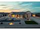 Inviting home exterior with elegant lighting, a well-manicured yard, and a large driveway at dusk at 460 W Chase St, San Tan Valley, AZ 85143