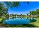 Scenic view of a pond with a fountain surrounded by lush greenery and houses at 7826 W Mcrae Way, Glendale, AZ 85308