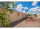 Exterior view of the home with stucco walls, small windows, and a gravel yard, set against a blue sky with palm trees at 8103 E Southern #303 Ave, Mesa, AZ 85209