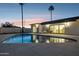 Backyard with refreshing pool, two chairs, sliding glass doors, and two palm trees at twilight at 8403 E Fairmount Ave, Scottsdale, AZ 85251