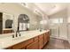 Bright bathroom featuring a large mirror, dual sinks, wood cabinets, and a walk-in shower at 8628 W Maui Ln, Peoria, AZ 85381