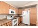 Cozy kitchen with modern microwave, matching white refrigerator, and wood cabinets at 8628 W Maui Ln, Peoria, AZ 85381