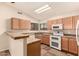 Well-equipped kitchen showcasing wood cabinets, white appliances, and tile backsplash at 8628 W Maui Ln, Peoria, AZ 85381
