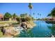 Scenic view of a tranquil pond with a rock waterfall, surrounded by palm trees and flowering plants at 8628 W Maui Ln, Peoria, AZ 85381