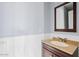 Bathroom with white wainscoting, a wooden framed mirror, and a tan countertop at 8750 W Granada Rd, Phoenix, AZ 85037