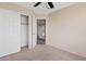 A bedroom features a ceiling fan, neutral carpeting, and a closet with doors open at 8750 W Granada Rd, Phoenix, AZ 85037