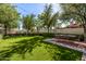 Manicured backyard with artificial turf, dining area and mature trees offers private outdoor living at 9310 S Bala Dr, Tempe, AZ 85284