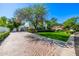 A long brick driveway leading to a well-maintained home with lush landscaping and mature trees at 9310 S Bala Dr, Tempe, AZ 85284