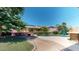 Lush backyard with vibrant foliage, a pool, and a cozy seating area around a fire pit at 10440 W Swayback Pass, Peoria, AZ 85383