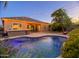 Night shot of a backyard featuring a pool, patio, lighted tree and kitchen at 10440 W Swayback Pass, Peoria, AZ 85383