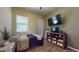 Simple bedroom with a large window, television, and a wooden entertainment center for storage and decor at 10440 W Swayback Pass, Peoria, AZ 85383