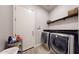 Well-lit laundry room includes a modern washer and dryer, storage shelves, and tile flooring at 10440 W Swayback Pass, Peoria, AZ 85383