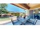Covered patio with outdoor seating offering a relaxing view of the backyard pool and green space at 10440 W Swayback Pass, Peoria, AZ 85383
