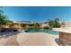 Inviting pool area with an outdoor kitchen, lush landscaping, and stylish stone accents at 10440 W Swayback Pass, Peoria, AZ 85383