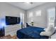 Well-lit bedroom featuring wood floors, a modern ceiling fan, and an entertainment area with a large TV at 1202 E Nolan Pl, Chandler, AZ 85249