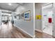 Well-lit hallway featuring wood flooring and decorative art leading to an open living space and bathroom at 1202 E Nolan Pl, Chandler, AZ 85249