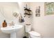 Well-lit half bathroom featuring a pedestal sink, toilet, and decorative shelving at 1528 N Balboa --, Mesa, AZ 85205