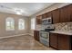 Well-lit kitchen featuring stainless steel appliances, tiled backsplash, dark wood cabinets and tiled flooring at 16525 W Tranquility Ln, Surprise, AZ 85387