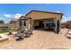 View of covered back patio with brick pavers, outdoor seating, and hot tub in the distance at 16756 S 181St Ln, Goodyear, AZ 85338