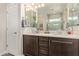 Bathroom showcasing double sinks with dark wood cabinets, framed mirrors, and a shower with tile accents at 16756 S 181St Ln, Goodyear, AZ 85338